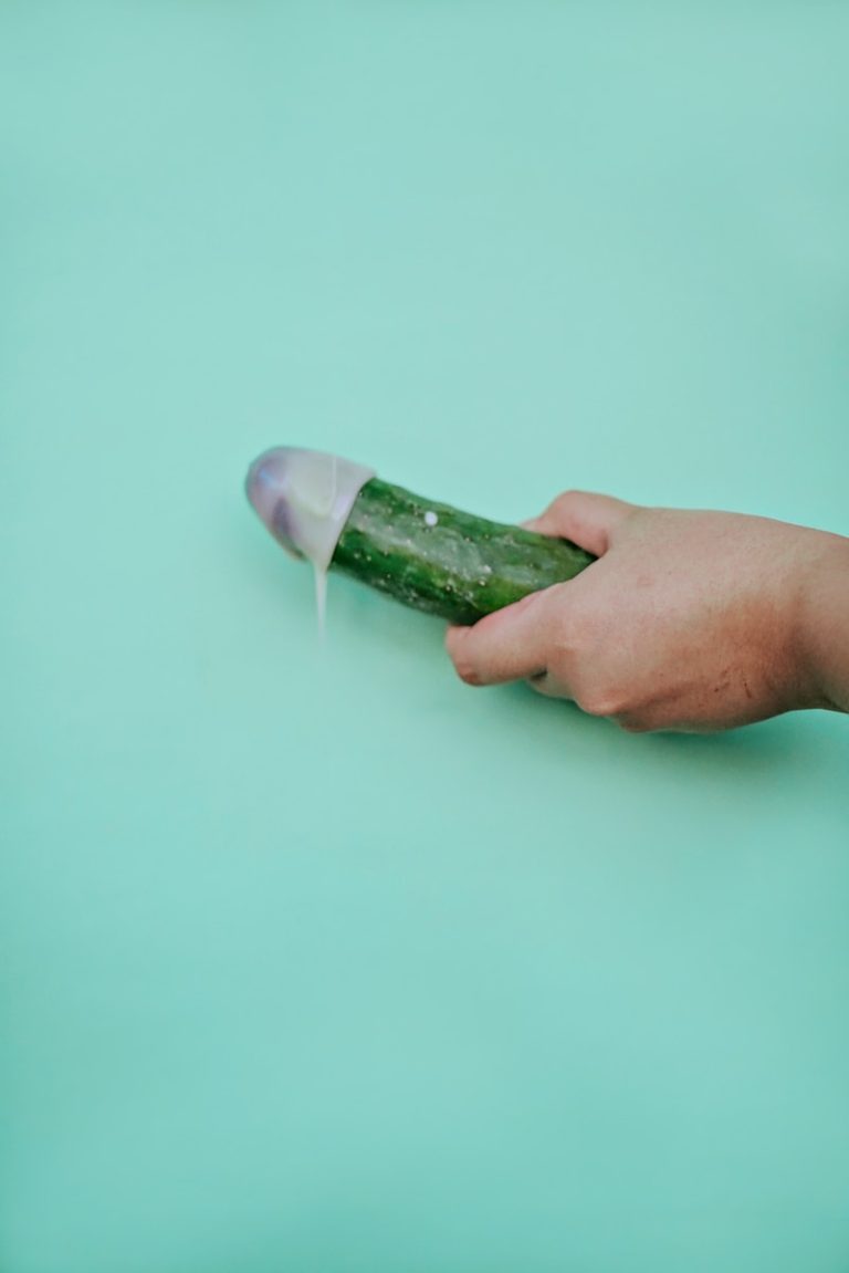 person holding green cucumber on teal table